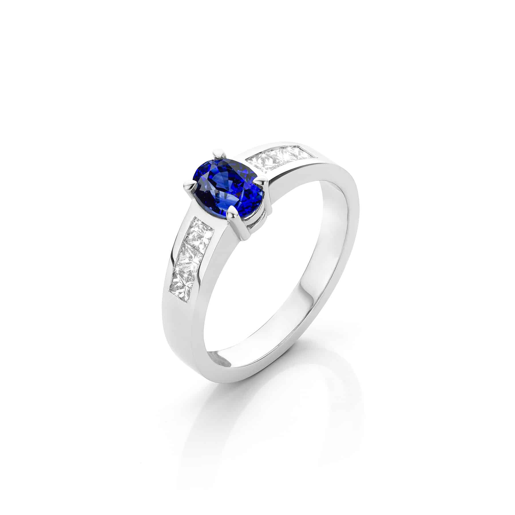 Blauwe saffier 1.15 ct. in 18 karaat witgouden ring met aan beide kanten 3 princess geslepen diamanten.